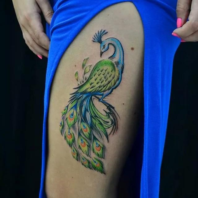 Tatuagem Pavão colorido na coxa. Tatuagem feminina. 